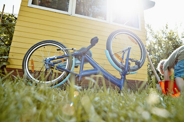 Junge repariert Fahrrad im Garten - RHF001038