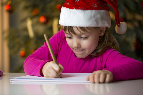 Kleines Mädchen mit Weihnachtsmütze schreibt eine Weihnachtsliste - ROMF000121