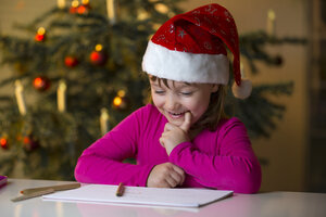 Kleines Mädchen mit Weihnachtsmütze schaut auf ihre Weihnachtsliste - ROMF000122