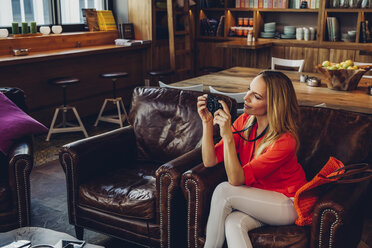 Blonde Frau sitzt in einem Café und fotografiert mit ihrer Digitalkamera - CHAF001020
