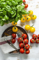 Gelbe und rote Tomaten, Basilikum mit einem Messer auf einem Holzbrett - ODF001154