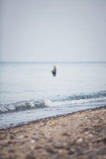 Deutschland, Nienhagen, Blick auf den Strand mit einem im Meer stehenden Angler im Hintergrund - ASCF000251