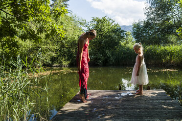 Frau mit nassem Kleid und Tochter auf Steg an einem See - TCF004780