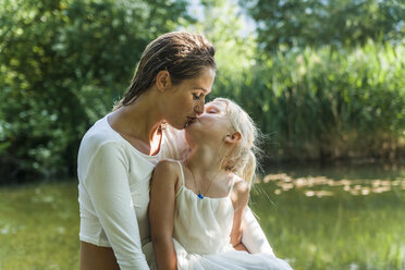 Mother and daughter kissing at a lake - TCF004787