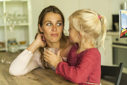 Mother looking at daughter holding glass - TCF004794