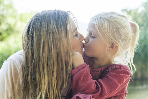 Mother and daughter kissing outdoors - TCF004804
