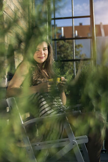 Young woman on balcony drinking morning coffee - RIBF000155