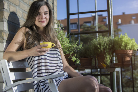 Junge Frau auf dem Balkon beim Morgenkaffee, lizenzfreies Stockfoto