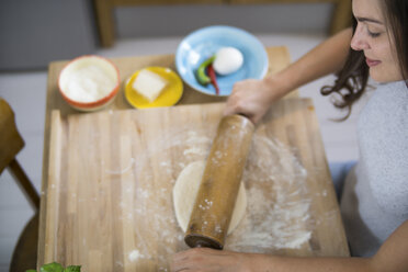 Young woman preparing pizza dough in kitchen - RIBF000190