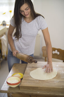 Junge Frau bereitet Pizzateig in der Küche vor - RIBF000194