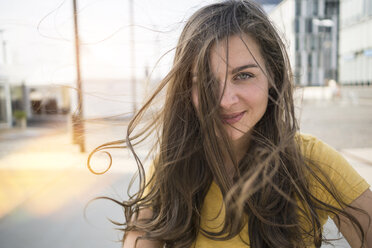 Germany, Cologne, portrait of smiling young woman with blowing hair - RIBF000212