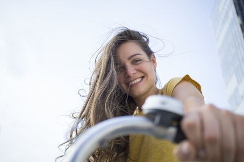 Portrait of smiling young woman holding handlebar of her bicycle - RIBF000217