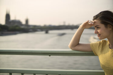 Germany, Cologne, young woman standing on Rhine bridge at evening twilight - RIBF000219