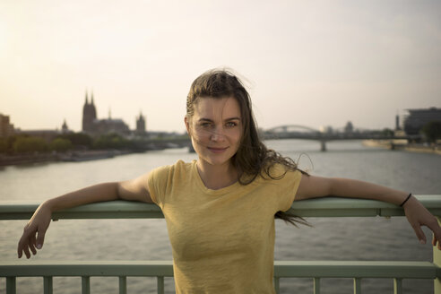 Deutschland, Köln, Porträt einer jungen Frau auf der Rheinbrücke in der Abenddämmerung - RIBF000220