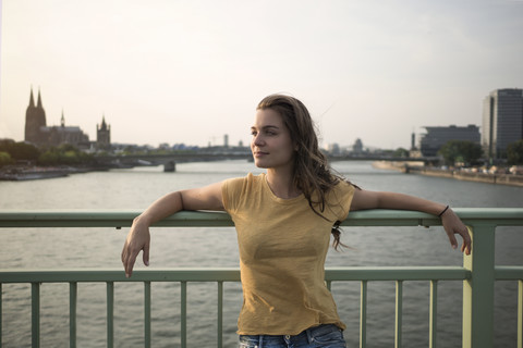 Deutschland, Köln, junge Frau steht in der Abenddämmerung auf der Rheinbrücke, lizenzfreies Stockfoto