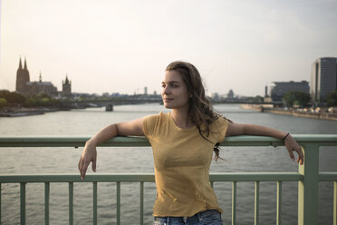 Deutschland, Köln, junge Frau steht in der Abenddämmerung auf der Rheinbrücke - RIBF000221