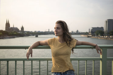 Germany, Cologne, young woman standing on Rhine bridge at evening twilight - RIBF000221