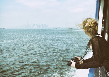 USA, New York City, Tourist mit Kamera auf der Staten Island Ferry mit Blick auf die Skyline von Manhattan und den East River - ONF000917