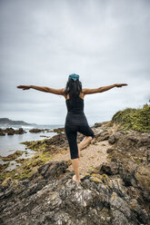 Spanien, Asturien, Gijon, Frau beim Yoga an einem Felsstrand - MGOF000389