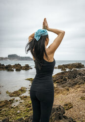 Spain, Asturias, Gijon, woman doing yoga on a rocky beach - MGOF000390