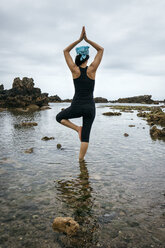 Spanien, Asturien, Gijon, Frau beim Yoga an einem Felsstrand - MGOF000376