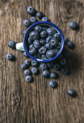 Emaillierte Tasse mit Blaubeeren auf Holz - MGOF000384