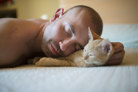 Man and kitten lying on bed, close-up stock photo