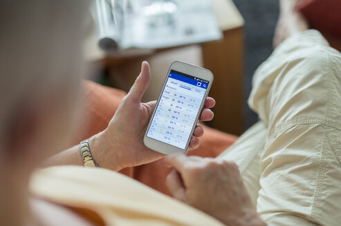 Ältere Frau betrachtet die Wettervorhersage auf dem Smartphone-Display - FRF000294