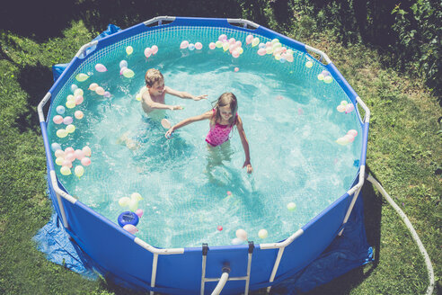 Junge und Mädchen im Schwimmbad, umgeben von Luftballons - SARF002066