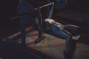 Female athlete doing bench presses with barbell - MADF000474