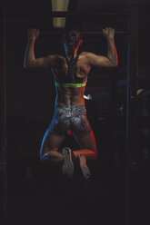 Female athlete doing chin ups, rear view - MADF000475