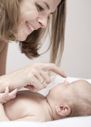 Junge Frau cremt Baby auf dem Wickeltisch liegend ein - MFRF000292