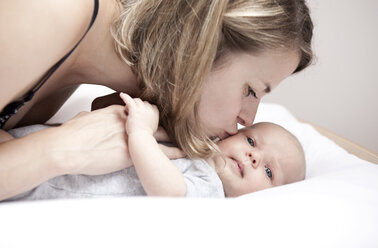 Junge Frau küsst Baby auf dem Wickeltisch liegend - MFRF000294