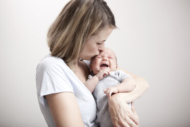 Junge Frau küsst weinendes Baby - MFRF000295