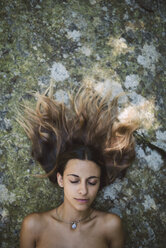 Porträt einer auf einem Felsen liegenden Frau mit geschlossenen Augen und zerzaustem Haar - RAEF000266