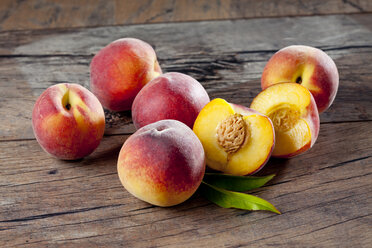 Whole and sliced peaches on wood - CSF025961