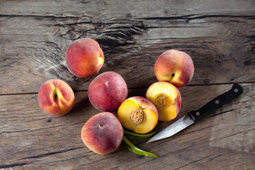 Whole and sliced peaches and a kitchen knife on wood - CSF025962