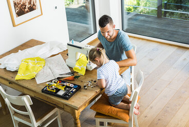 Vater und Tochter zu Hause an der Nähmaschine - UUF005122