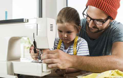 Vater und Tochter zu Hause an der Nähmaschine, lizenzfreies Stockfoto