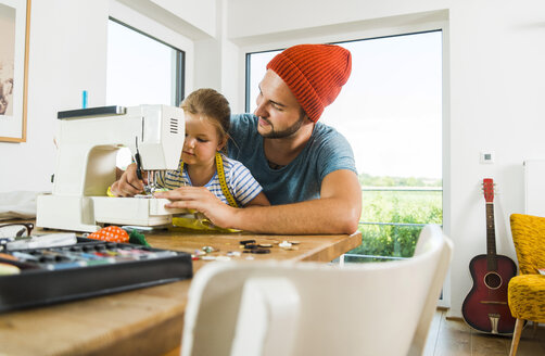 Father and daughter at home using sewing machine - UUF005137