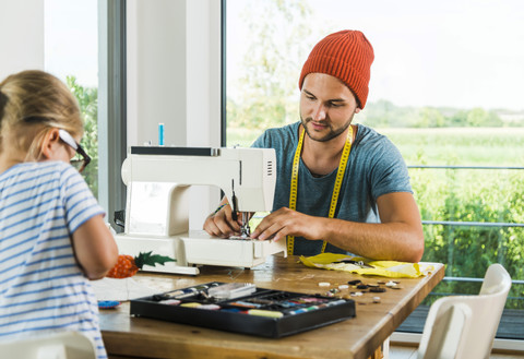 Vater und Tochter zu Hause an der Nähmaschine, lizenzfreies Stockfoto