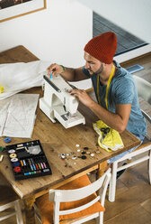 Young man at home using sewing machine - UUF005203