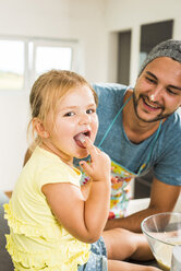 Vater und Tochter backen in der Küche und probieren Teig - UUF005177