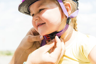 Close-up of father closing daughter's bicycle helmet - UUF005190