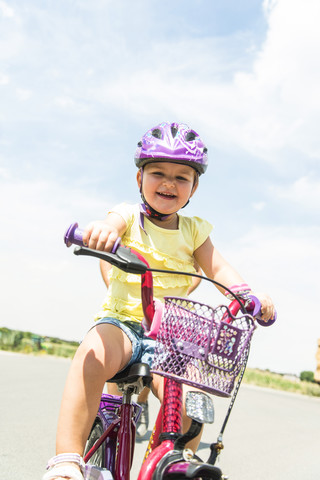 Glückliches kleines Mädchen fährt Fahrrad, lizenzfreies Stockfoto