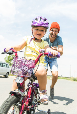 Vater begleitet Tochter auf dem Fahrrad, lizenzfreies Stockfoto