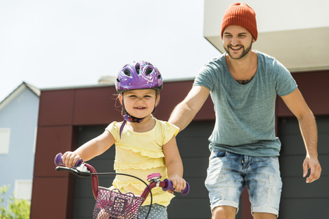 Vater unterstützt Tochter auf dem Fahrrad, lizenzfreies Stockfoto