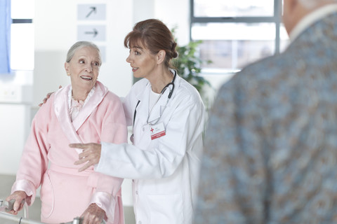 Arzt führt älteren Patienten auf dem Krankenhausflur, lizenzfreies Stockfoto