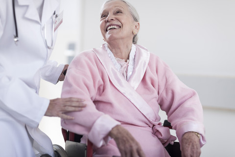 Arzt und lächelnder älterer Patient im Rollstuhl, lizenzfreies Stockfoto