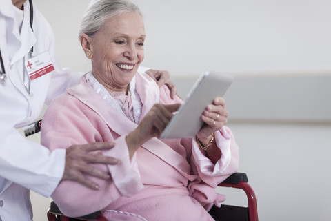 Lächelnder älterer Patient im Rollstuhl mit digitalem Tablet, lizenzfreies Stockfoto